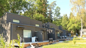 Une rangée de chalets modernes dotés de grandes fenêtres, d’un espace extérieur aménagé et d’un sentier en gravier.
