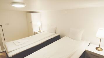 A hotel room with two single beds, a bedside table with a lamp, and a mirror on the wall.
