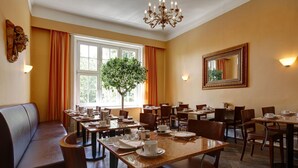 A dining area with tables set for service, a large window with curtains, a chandelier, and a mirror on the wall. - Hotel Amsterdam (Hamburg)