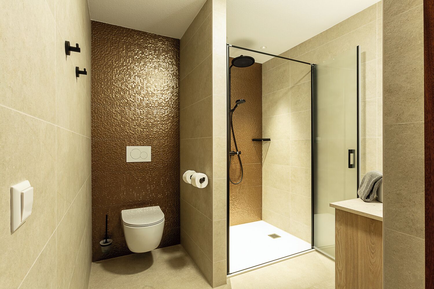 A modern bathroom with a glass shower enclosure, a toilet, and a sink with a towel.