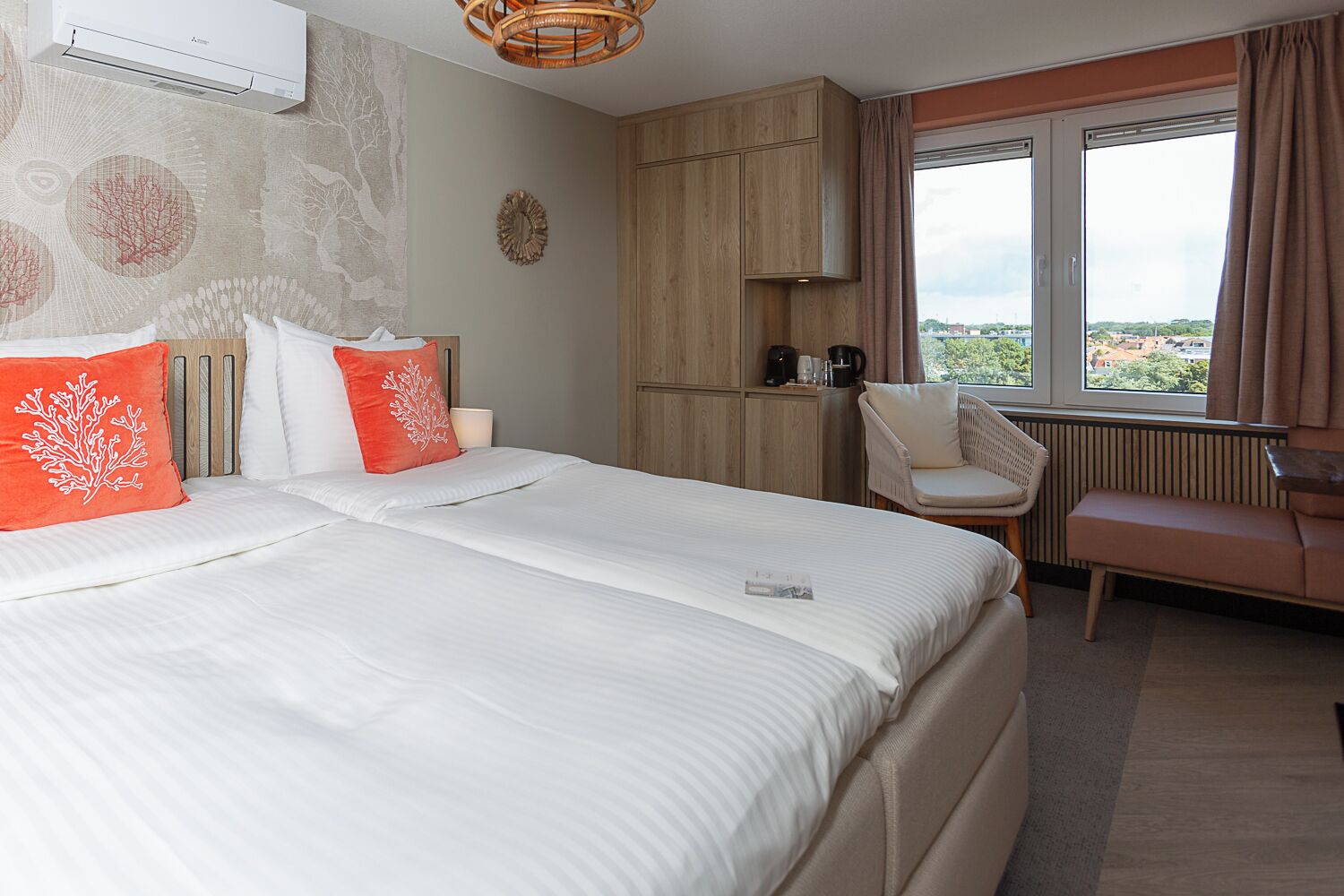 Une chambre d’hôtel avec un grand lit, une chaise, un bureau et une vue sur la ville par la fenêtre.