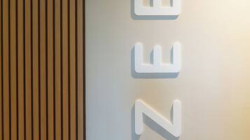 A wall with vertical wooden slats and a white illuminated sign with the letters "ZEE".