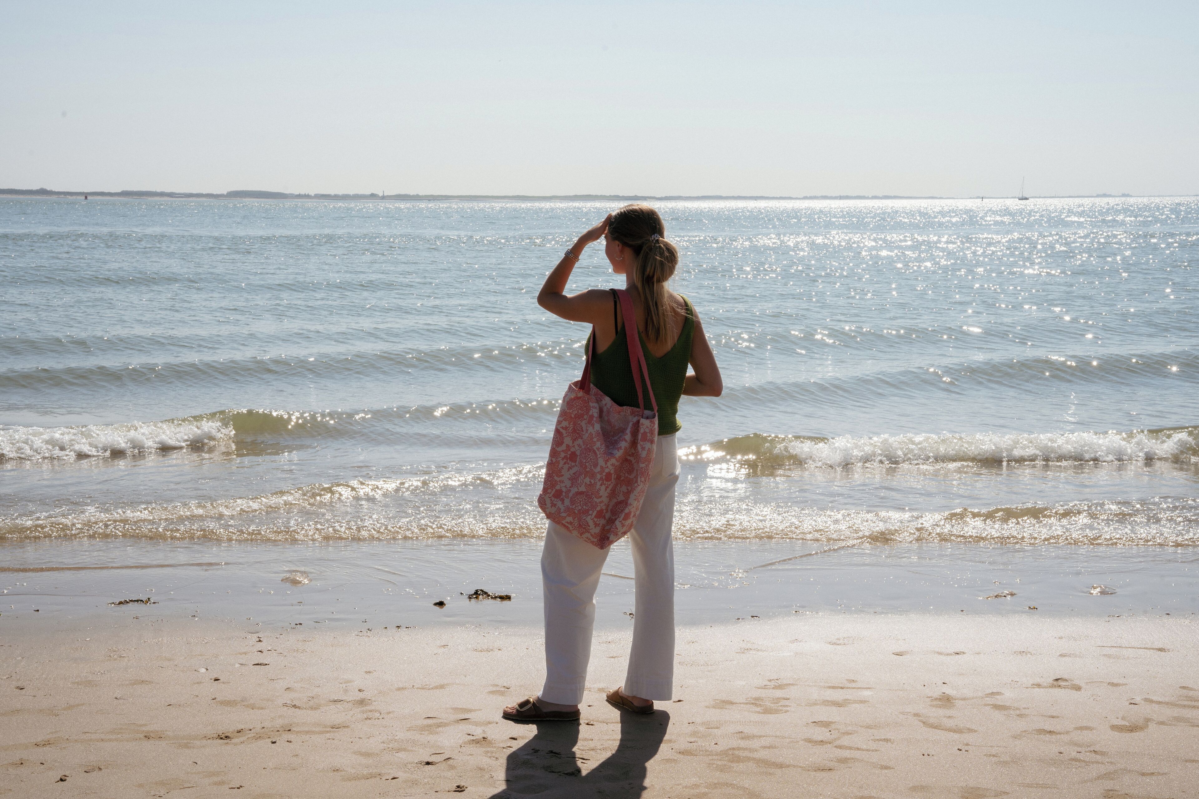 A woman standing on a beach with waves in the background.