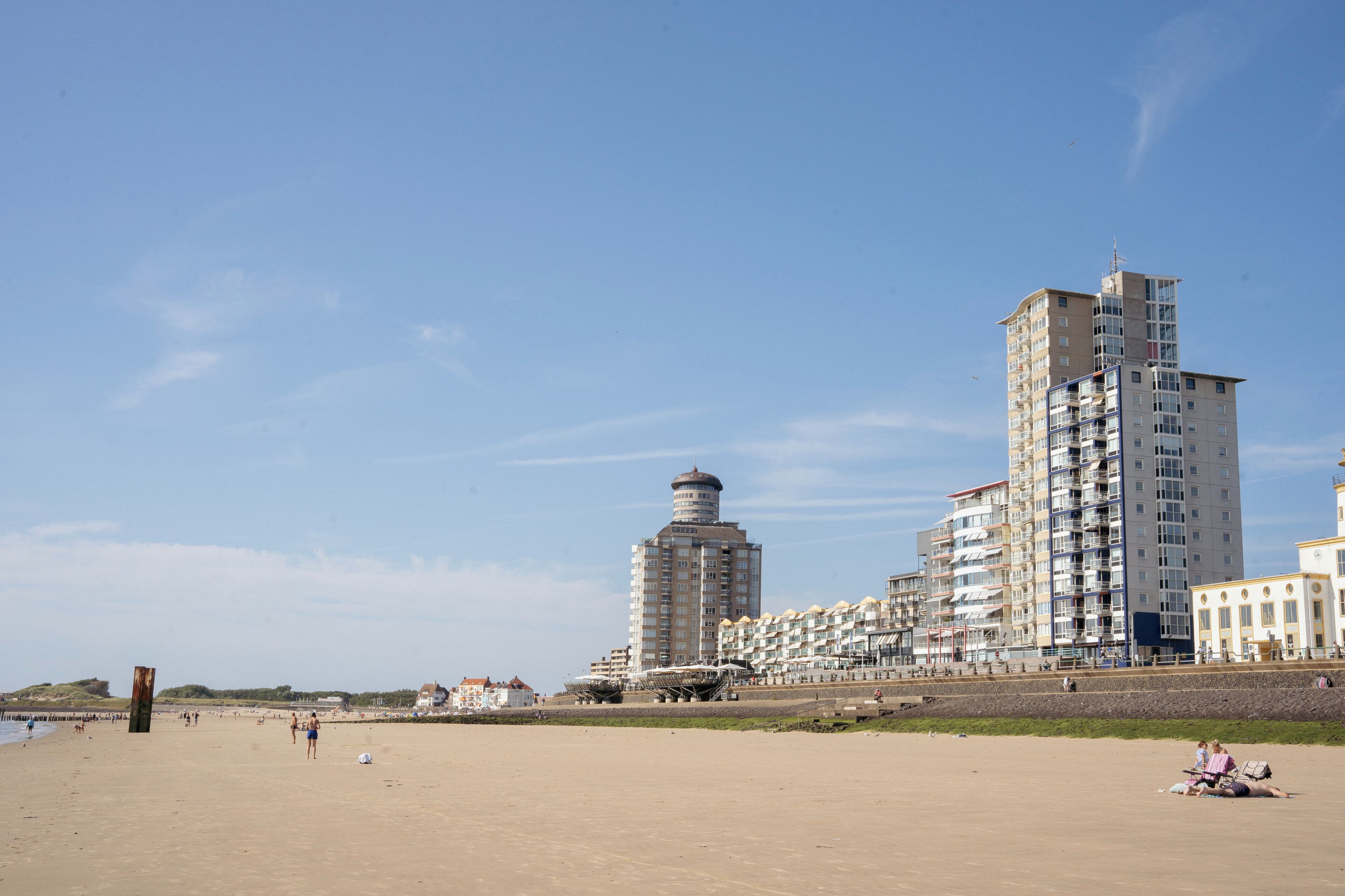 Une plage avec un grand immeuble et une tour plus petite, tous deux dotés de nombreux étages et de balcons.