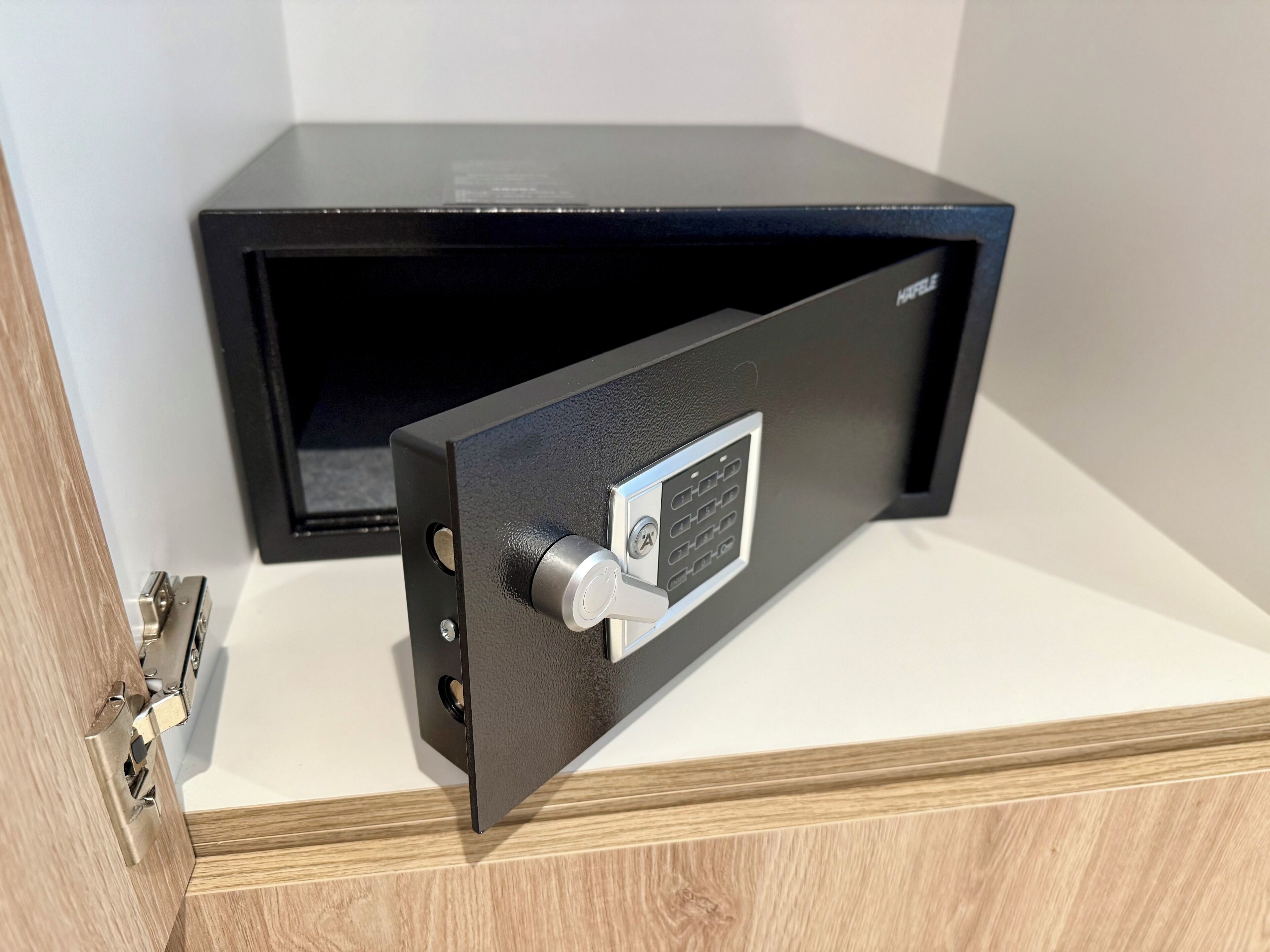 Un coffre-fort noir doté d’un cadran à combinaison et d’un trou de serrure, posé sur une surface blanche.