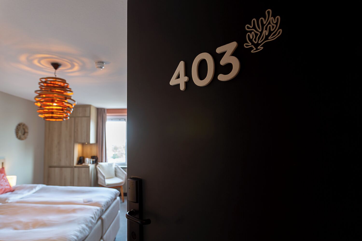 A hotel room with a bed, a desk, a chair, and a wall-mounted number '403'.