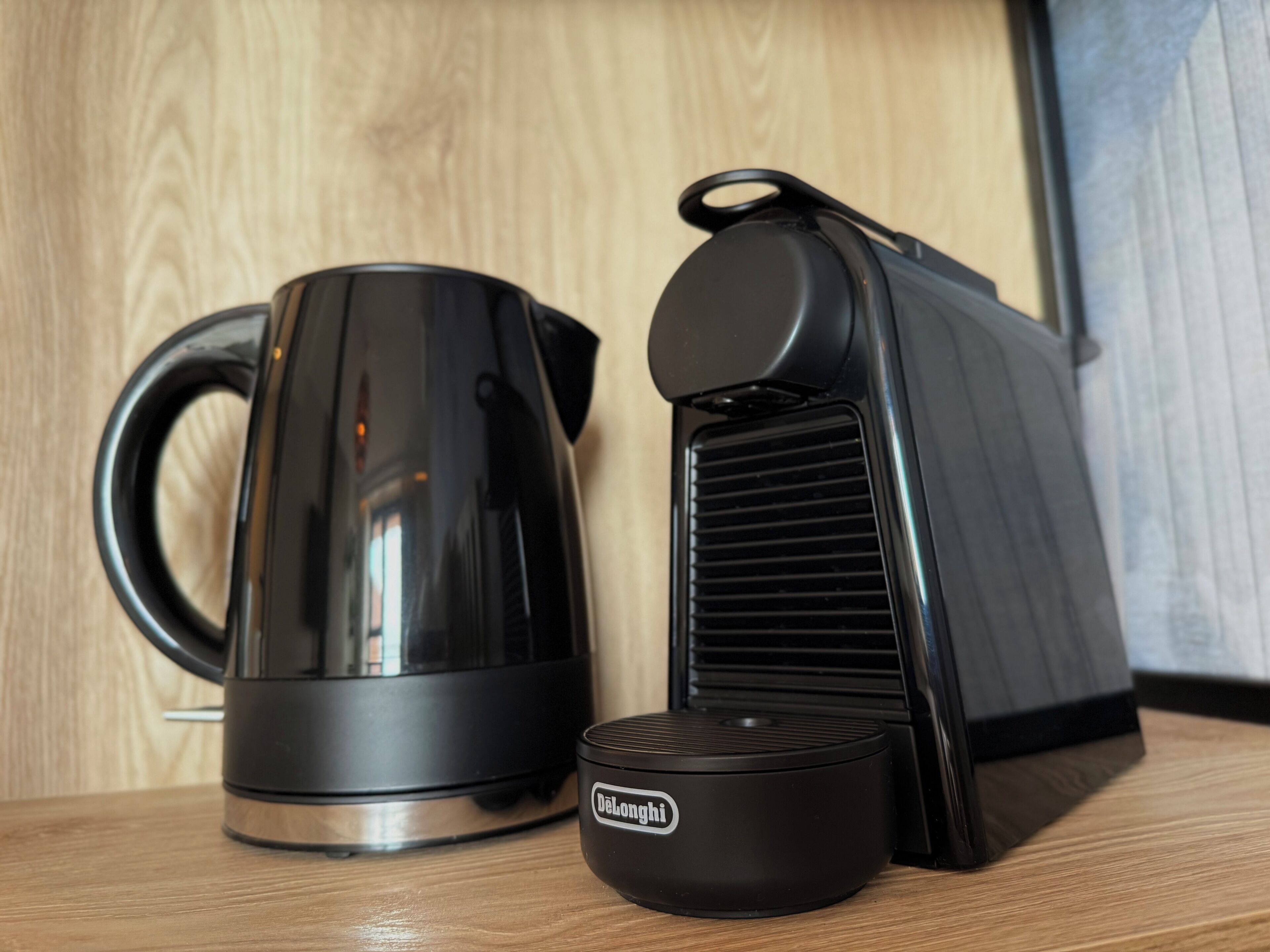 Una tetera eléctrica negra y una cafetera eléctrica negra sobre una superficie de madera.