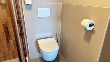 Un baño con un inodoro, un dispensador de toallas de papel y un porta papel higiénico en la pared.