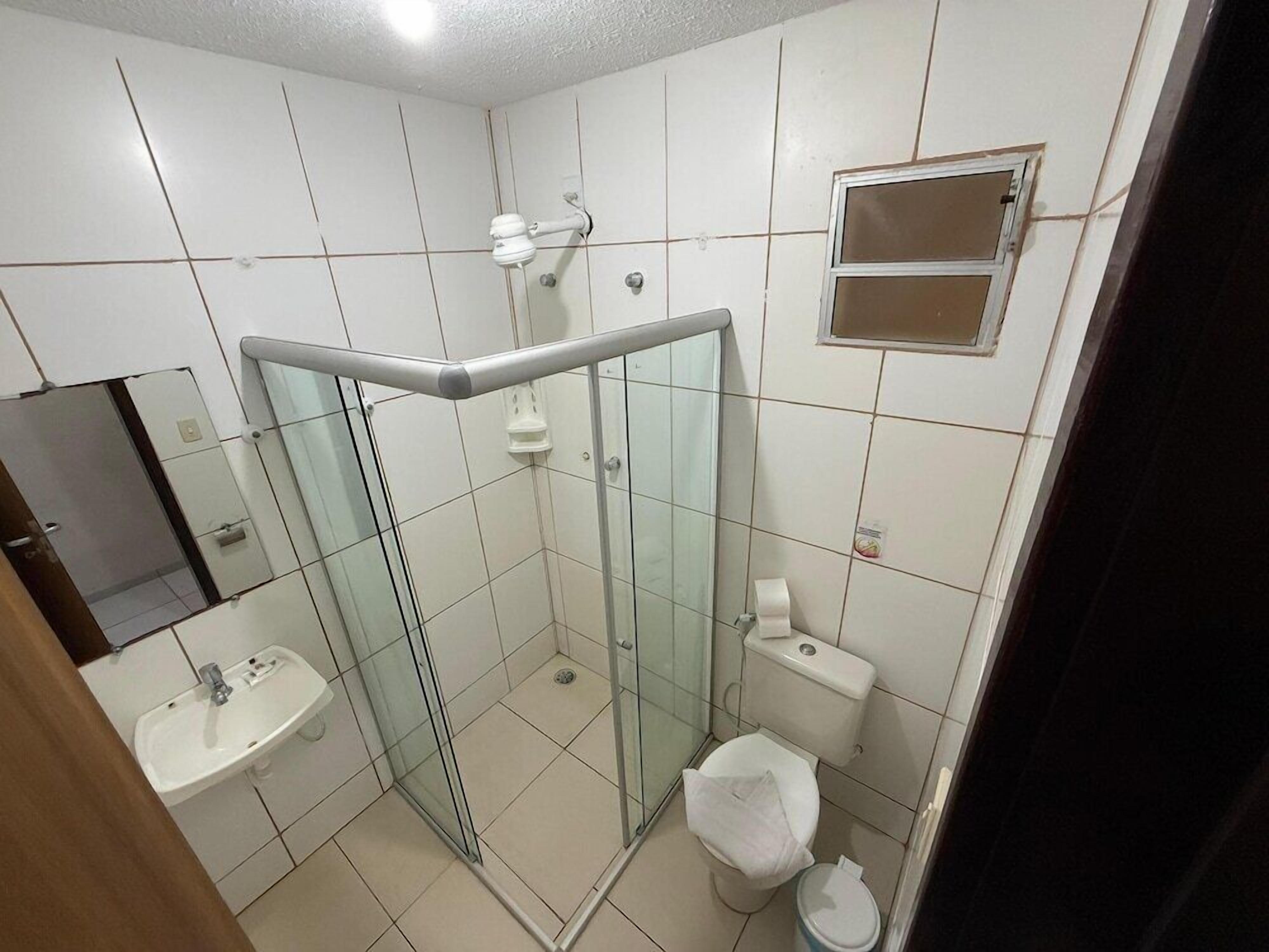 A bathroom with a glass shower enclosure, a sink, a toilet, and a mirror.