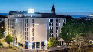 Un hôtel moderne, doté de plusieurs étages, d’une tour imposante et offrant une vue sur la mer.
