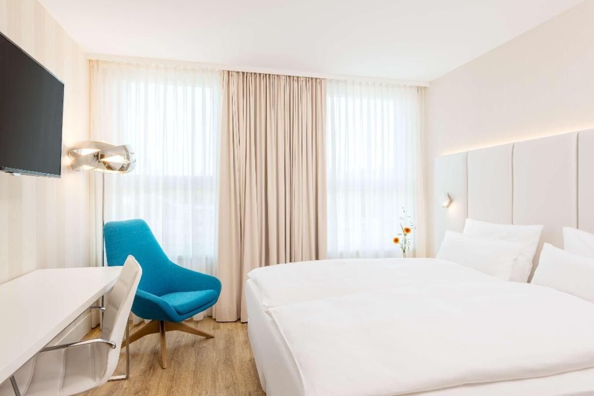 Une chambre d’hôtel avec un lit, un bureau, une chaise et un téléviseur.