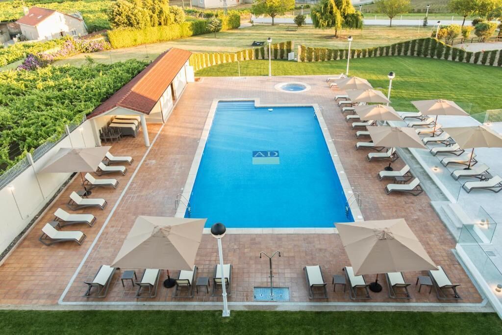 A swimming pool with lounge chairs and umbrellas, surrounded by a landscaped garden.