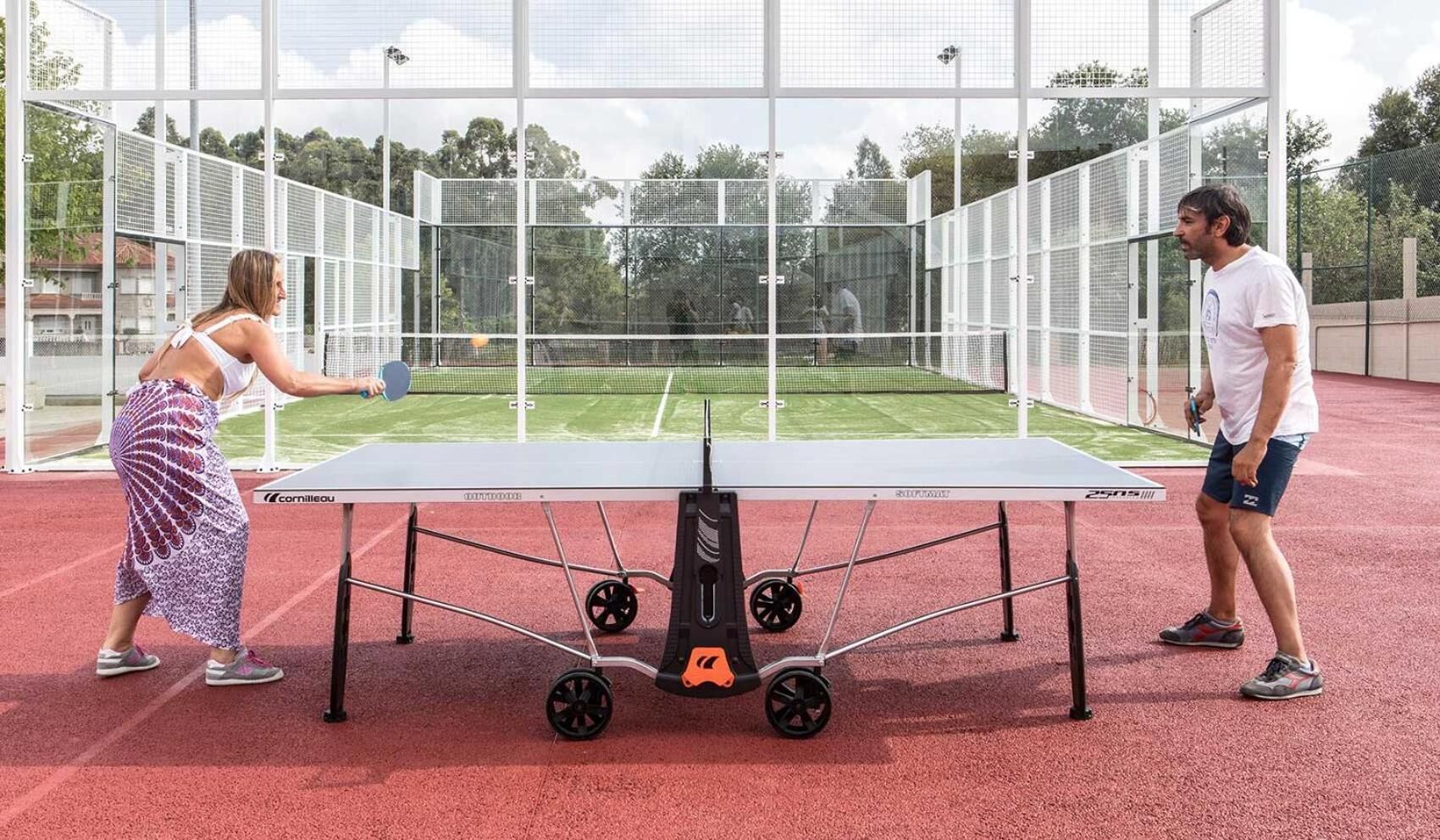 A table tennis table with a net in an outdoor sports facility.