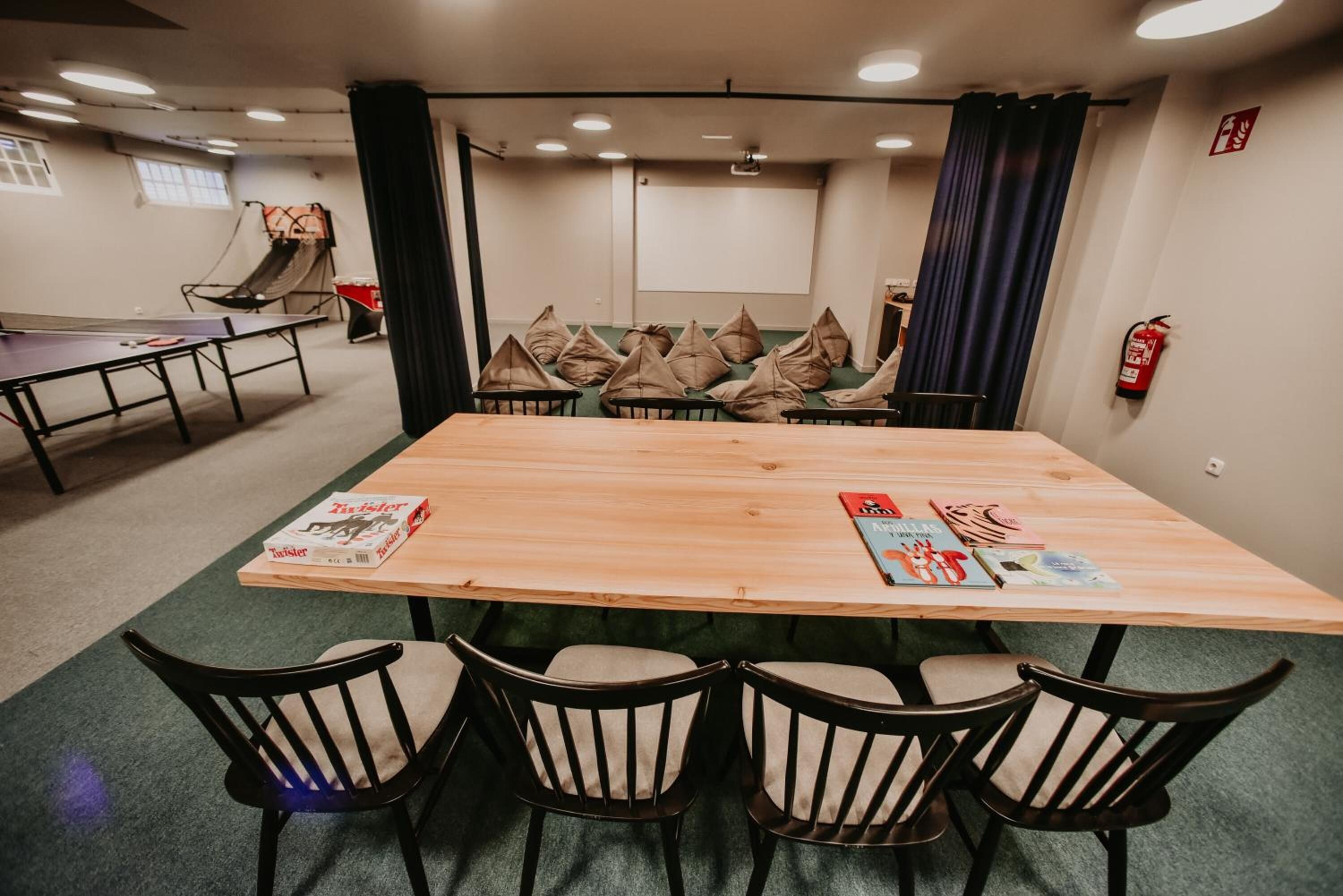 Un salón de conferencias con una mesa larga, cuatro sillas y una pantalla para proyector.