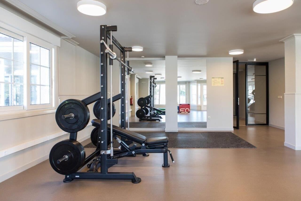 Un gimnasio con equipamiento de levantamiento de pesas, una banca y un espejo.