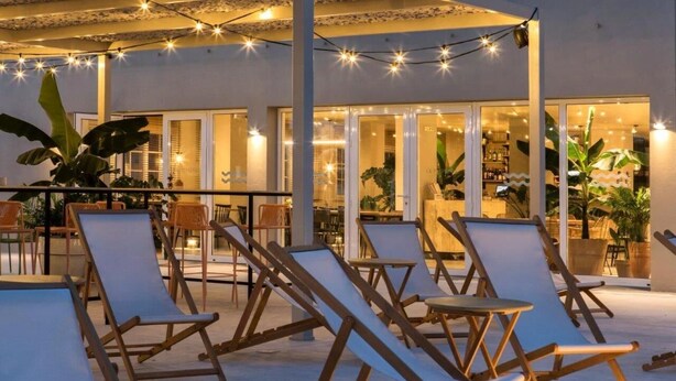 An outdoor seating area with lounge chairs and string lights. - Apartamentos Dena (Meano)