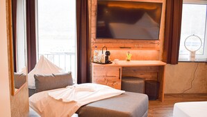 A modern hotel room with a large flat-screen TV, a wooden desk, a comfortable bed, and a small balcony with a view. - Hotel Winzerhaus Gaertner an der Loreley (Sankt Goar)