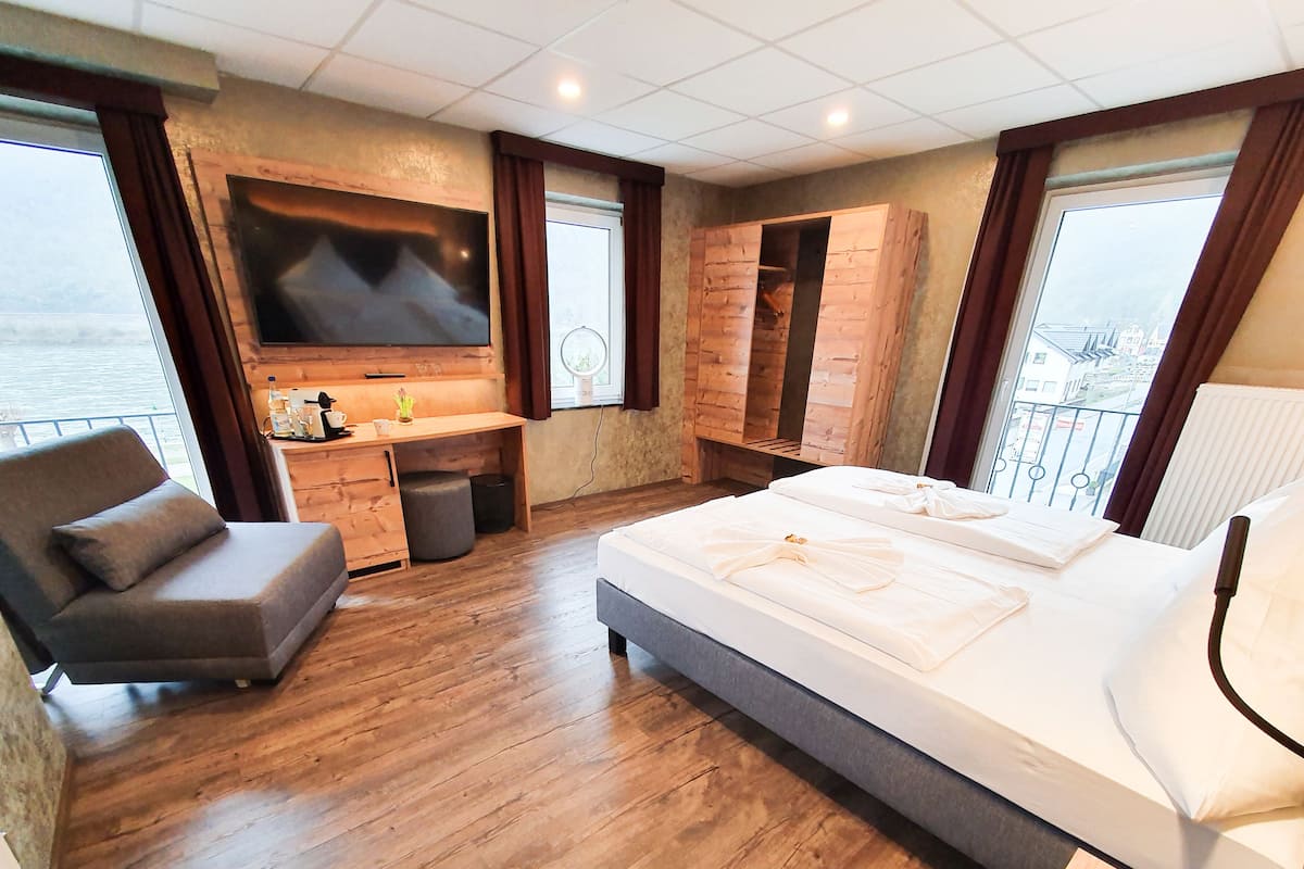 Quarto de hotel moderno com uma cama grande, uma escrivaninha, televisão e vista para o mar.