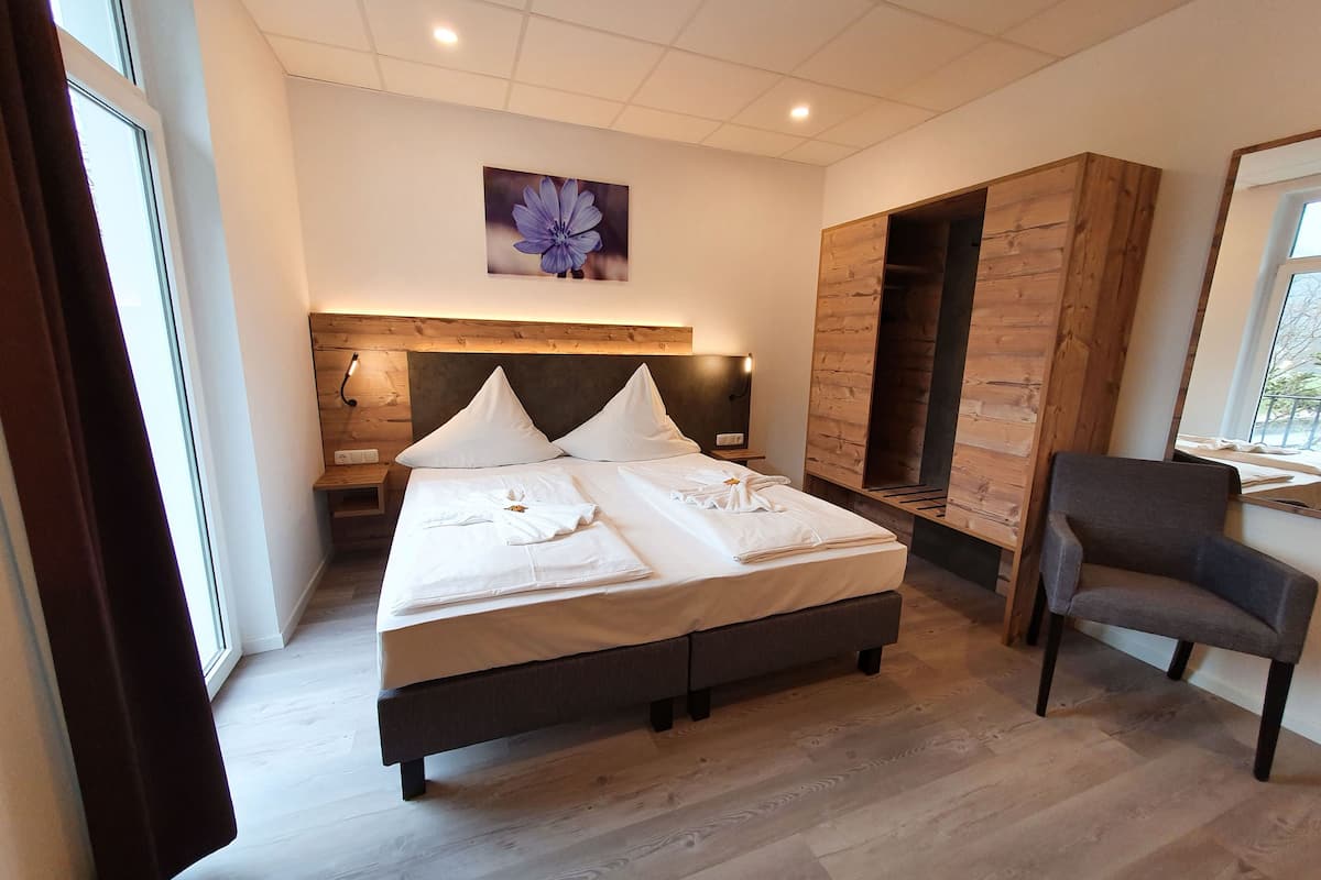 Quarto moderno com uma cama grande, um guarda-roupa de madeira, uma escrivaninha e uma cadeira.