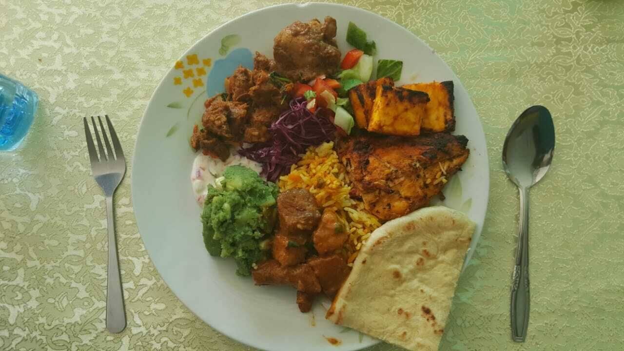 A plate of food with various dishes including grilled meat, rice, and vegetables.