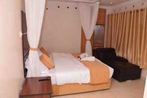 A hotel room with a bed, a chair, a TV, and curtains. - Nairobi Glory Palace Hotel (Nairobi)