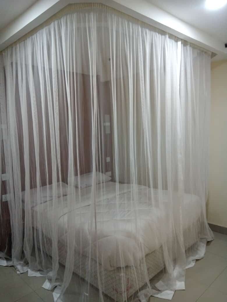 Un dormitorio con una cama cubierta por un dosel blanco translúcido.