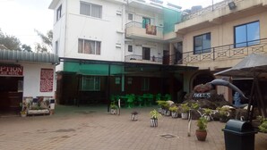 Un patio de hotel con un área de estar cubierta, plantas en macetas y un letrero que indica una zona de información para huéspedes.