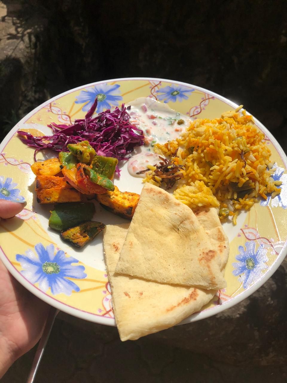 A plate with yellow rice, grilled vegetables, a piece of flatbread, and a side of red cabbage.