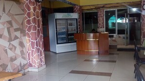 Un hall con mostrador de recepción, refrigerador y pared con diseño.