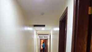 Un largo pasillo estrecho con piso de baldosas brillantes y puertas de madera a un lado.