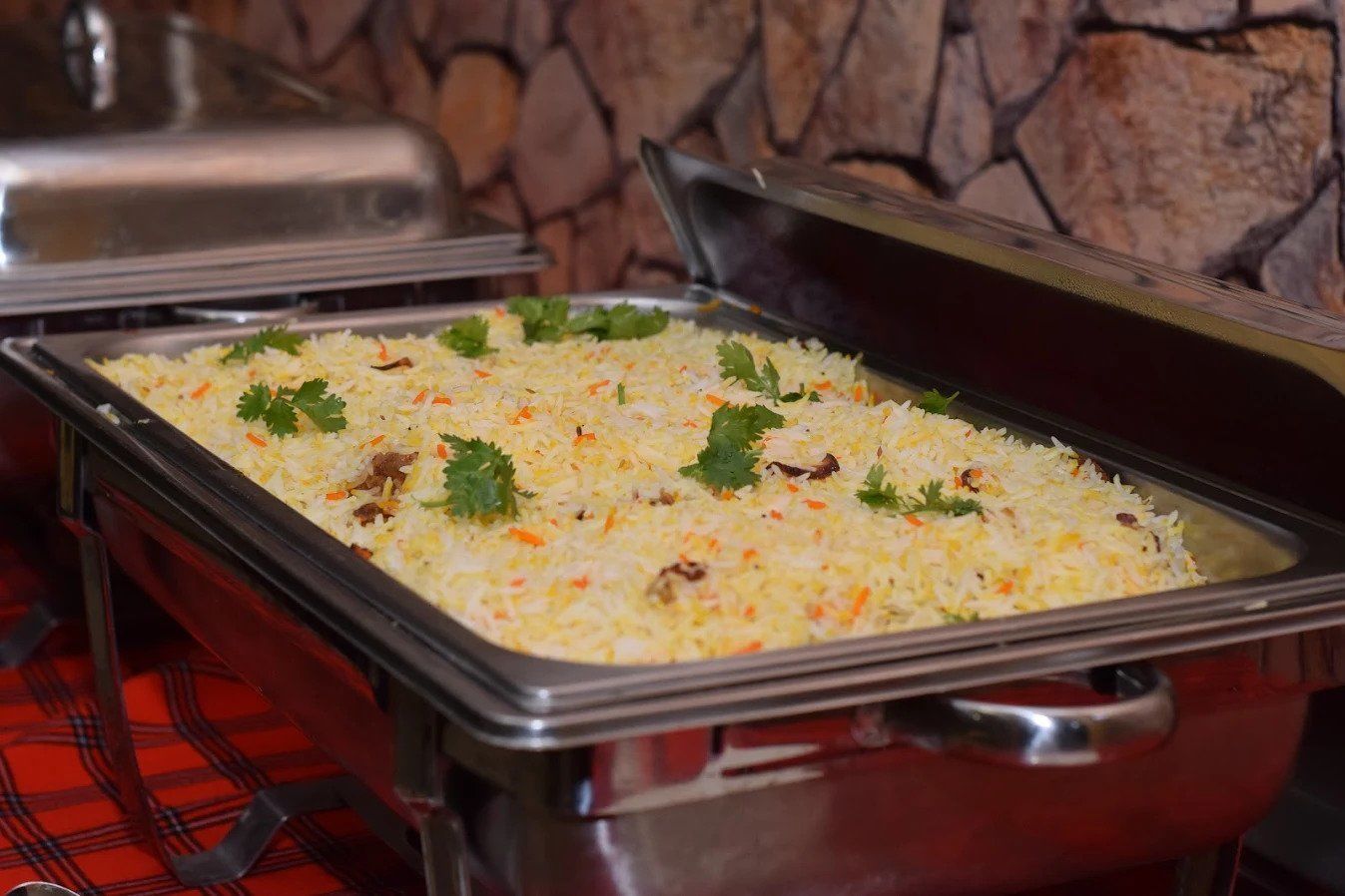Una mesa de buffet con una bandeja de arroz adornado con cilantro.