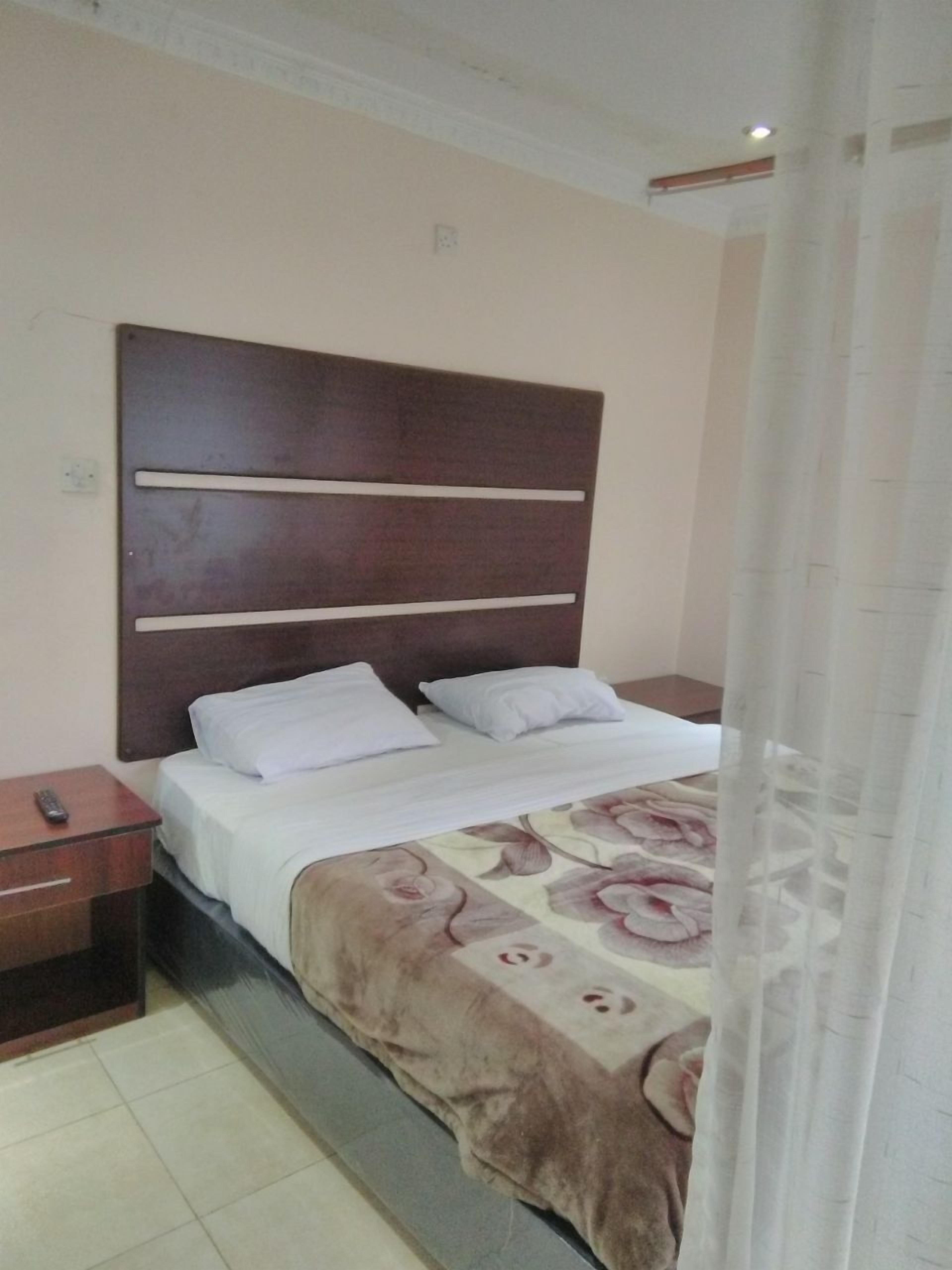 A hotel room with a bed, a nightstand, and a curtain.