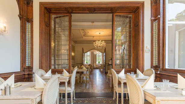 Un comedor formal con paneles de madera, una araña y un piso estampado.