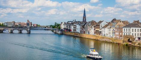 A river with a boat, a bridge, and historic buildings along the riverbank.
