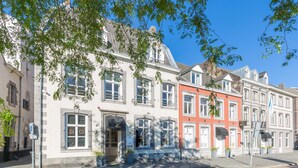 Una hilera de edificios tradicionales de estilo europeo con grandes ventanales y una calle adoquinada.