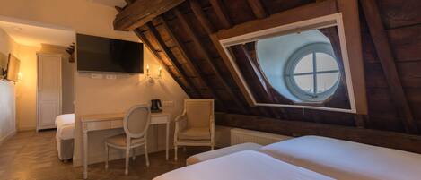 A bedroom with a wooden ceiling, a round window, a desk, a chair, and a bed.