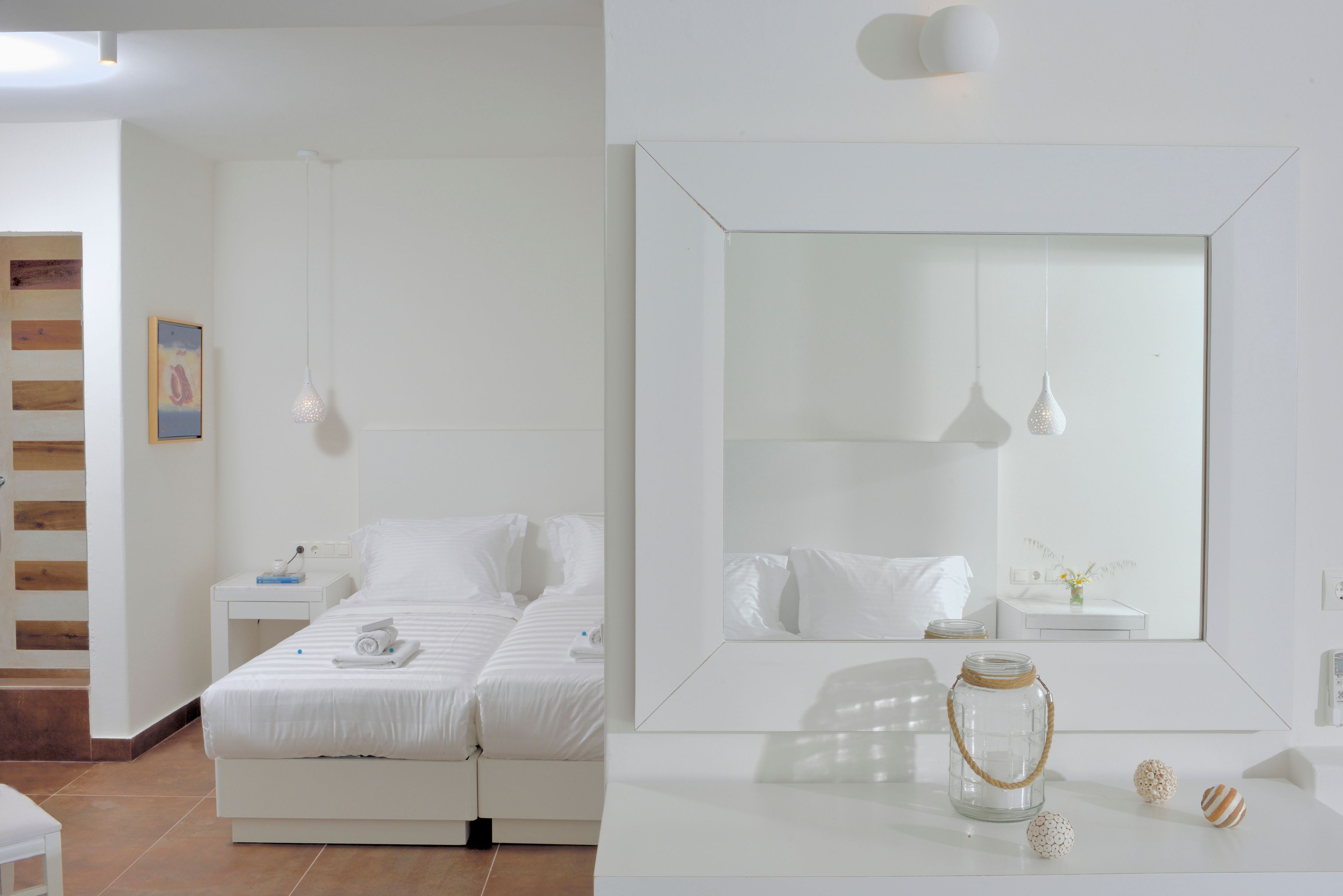 A modern bedroom with a large mirror, a bed, bedside tables, and a small table with decorative items.