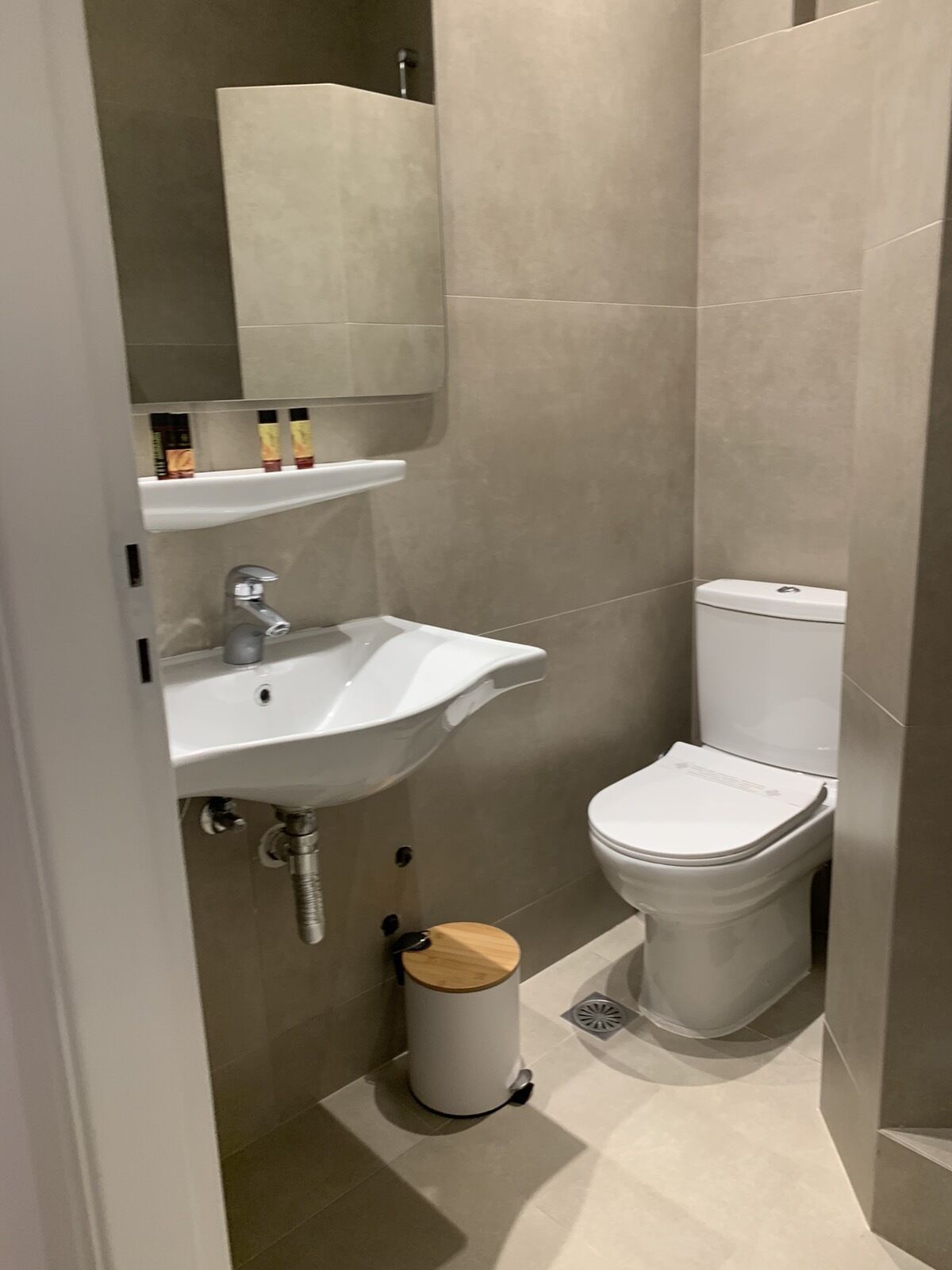 Une petite salle de bain moderne avec un lavabo blanc, des toilettes et une poubelle.