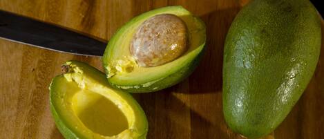 A halved avocado on a wooden cutting board.
