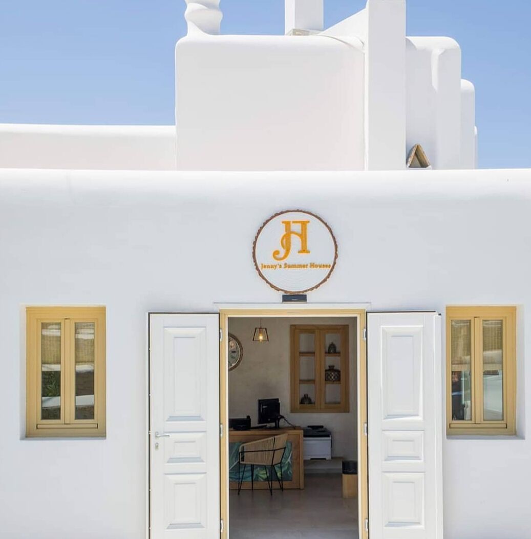 Un bâtiment blanc avec une enseigne indiquant « La maison d’été de Jenny » au-dessus de l’entrée.