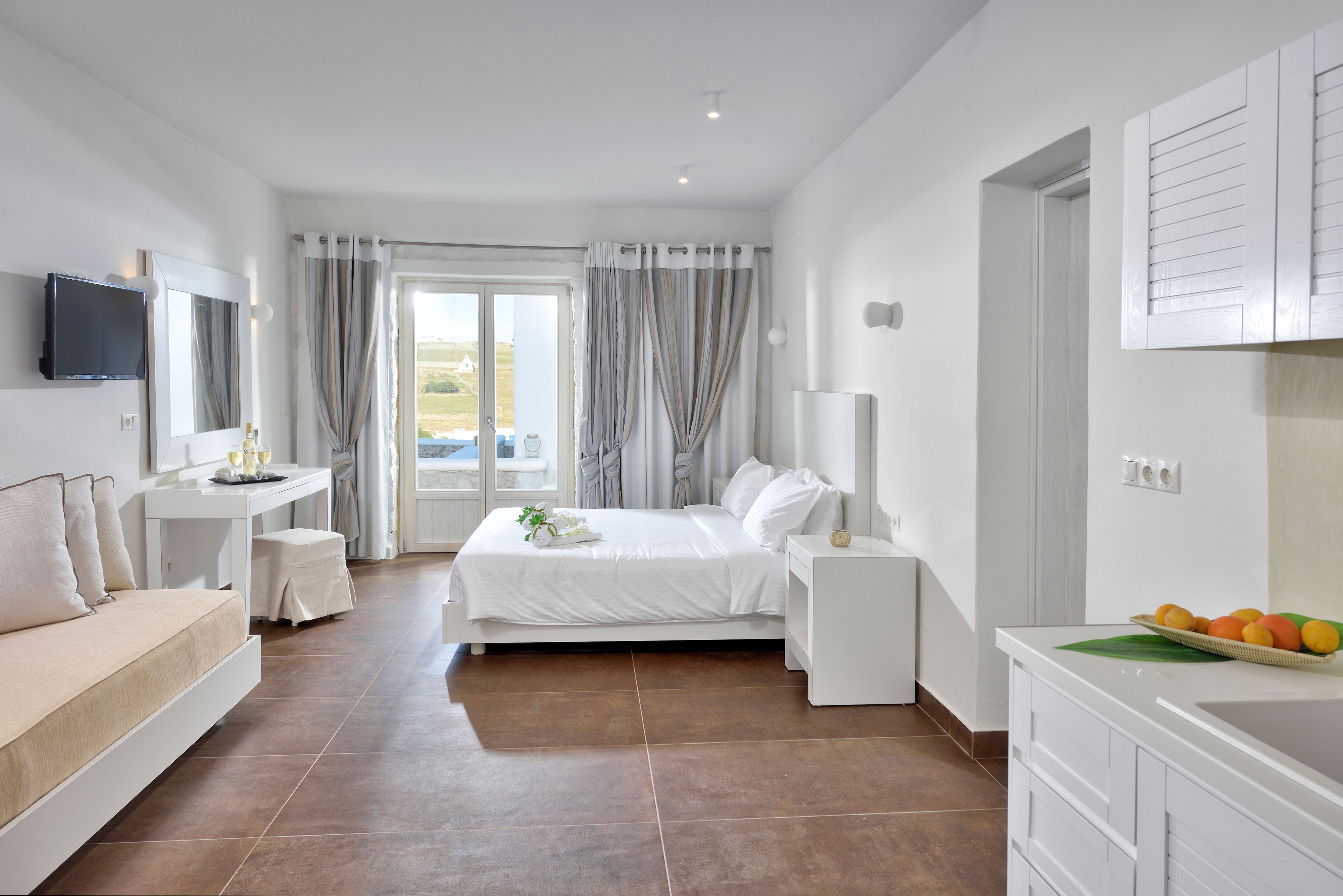 Una habitación de hotel moderna con una cama, un escritorio, un televisor y vistas al exterior.