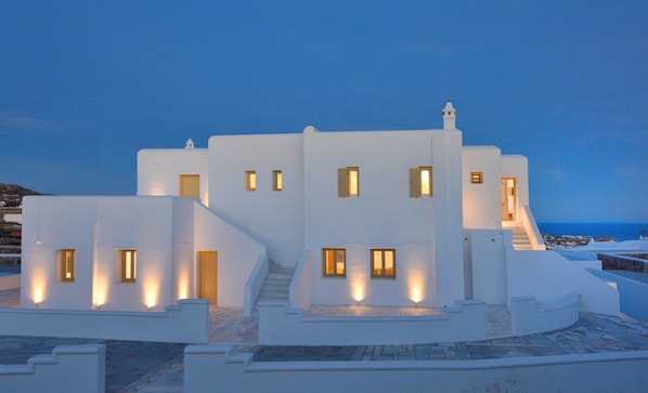 A white building with multiple windows and a staircase leading to the entrance.