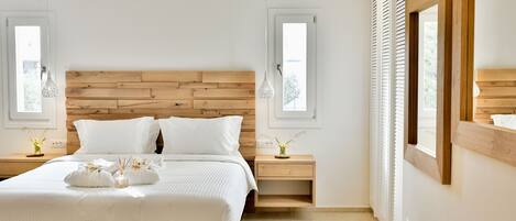 A modern bedroom with a wooden headboard, a large bed with white bedding, two bedside tables with lamps, and a wooden bench.