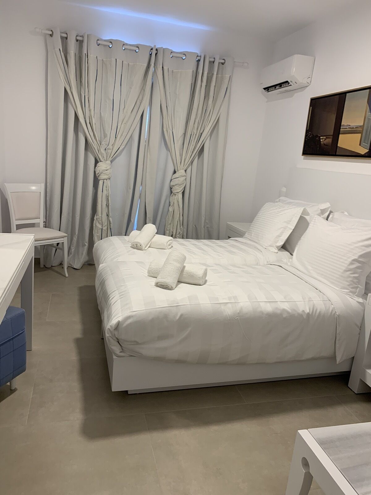 A neatly arranged bedroom with a bed, a chair, a desk, and curtains.
