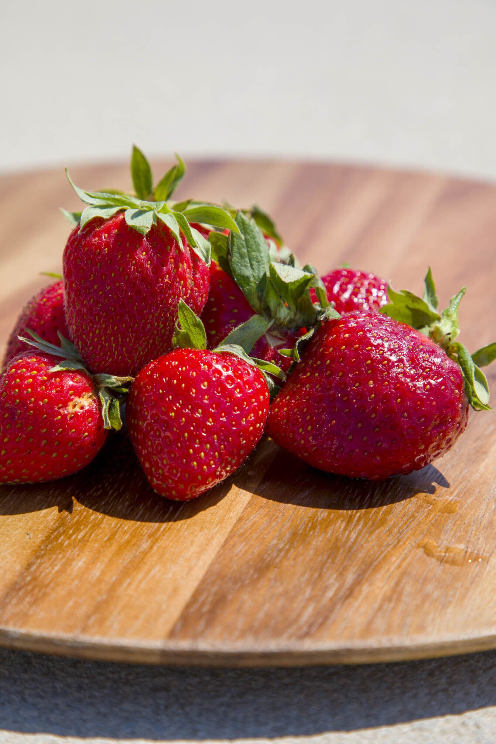 A wooden surface with several strawberries.