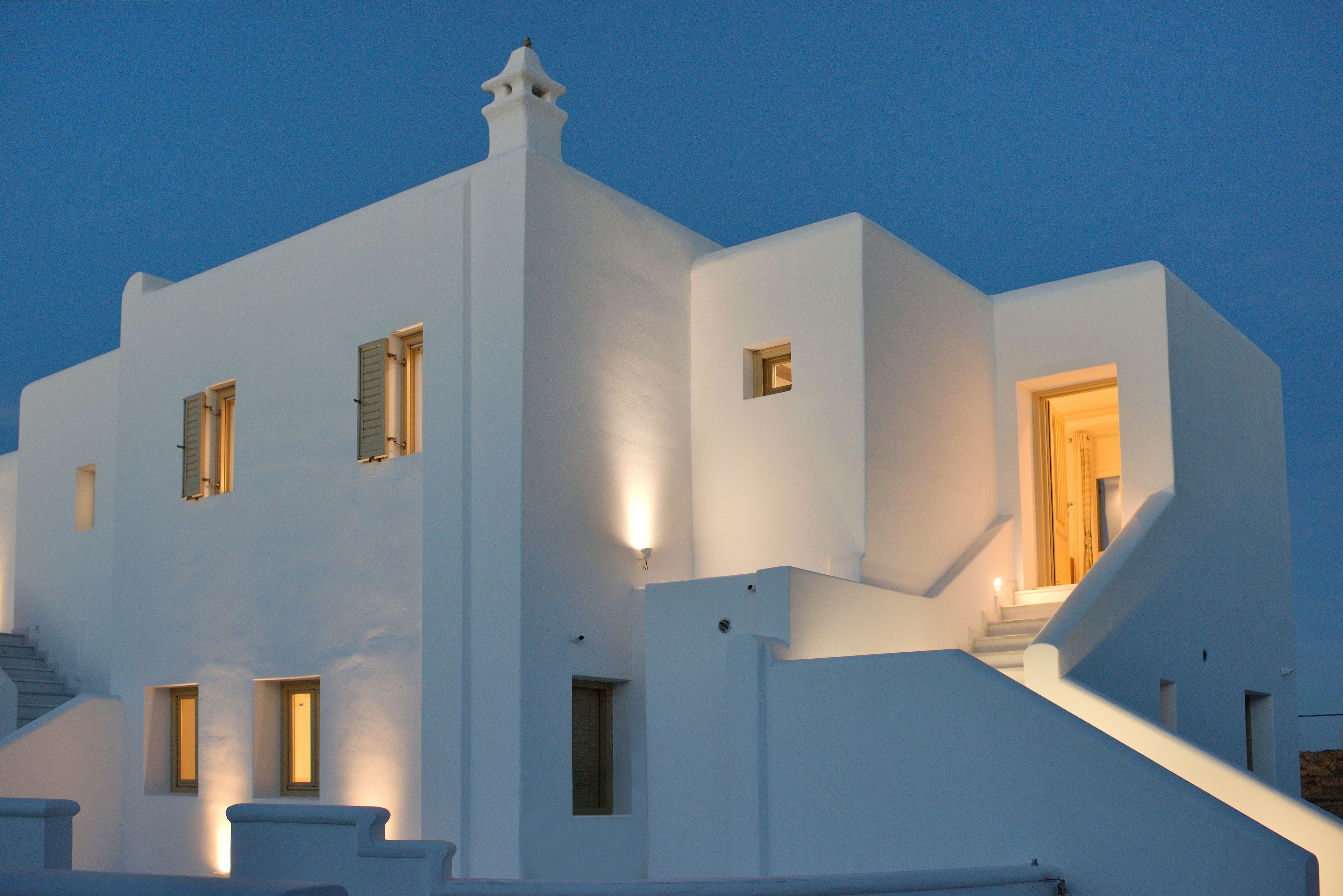 A white building with multiple windows and a staircase leading to an upper level.