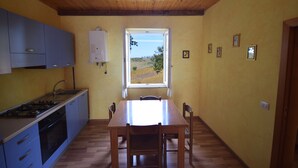 Une cuisine avec un plafond en bois, une fenêtre donnant sur l’extérieur et une table à manger avec des chaises.