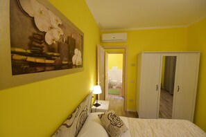 A hotel room with a bed, a nightstand, a lamp, a wardrobe, and a painting on the wall. - Agriturismo Al Rifugio DiVino (Belvedere Ostrense)