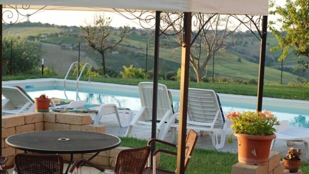 Un espace extérieur aménagé avec une piscine, des chaises longues et une table.