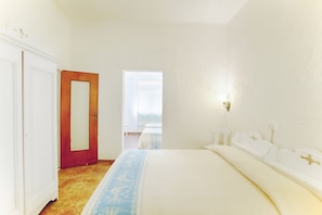 Une chambre à coucher comprenant un lit, une armoire, une porte et un luminaire fixé au mur.